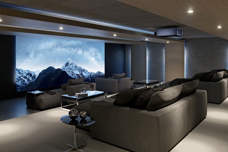 A home movie theater with tiered chaise lounges, a Sony projector, and a large movie screen depicting snowy mountains.